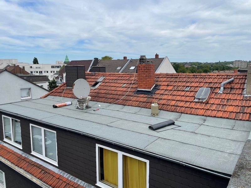 Flachdach eines Mehrfamilienhauses mit neu verlegter Bitumenbahn während der Abdichtung