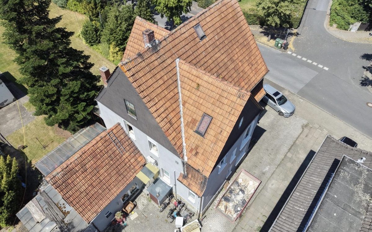Älteres Ziegeldach mit verwitterten Tonziegeln und undichter Gaube vor der Reparatur, Drohnenaufnahme